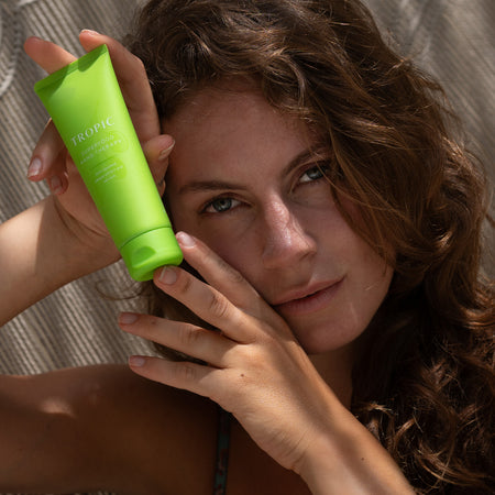Model is holding Superfood hand therapy in her hands. The product is in a green tube with white writing. It contains olive squalane, papaya & oat milk.